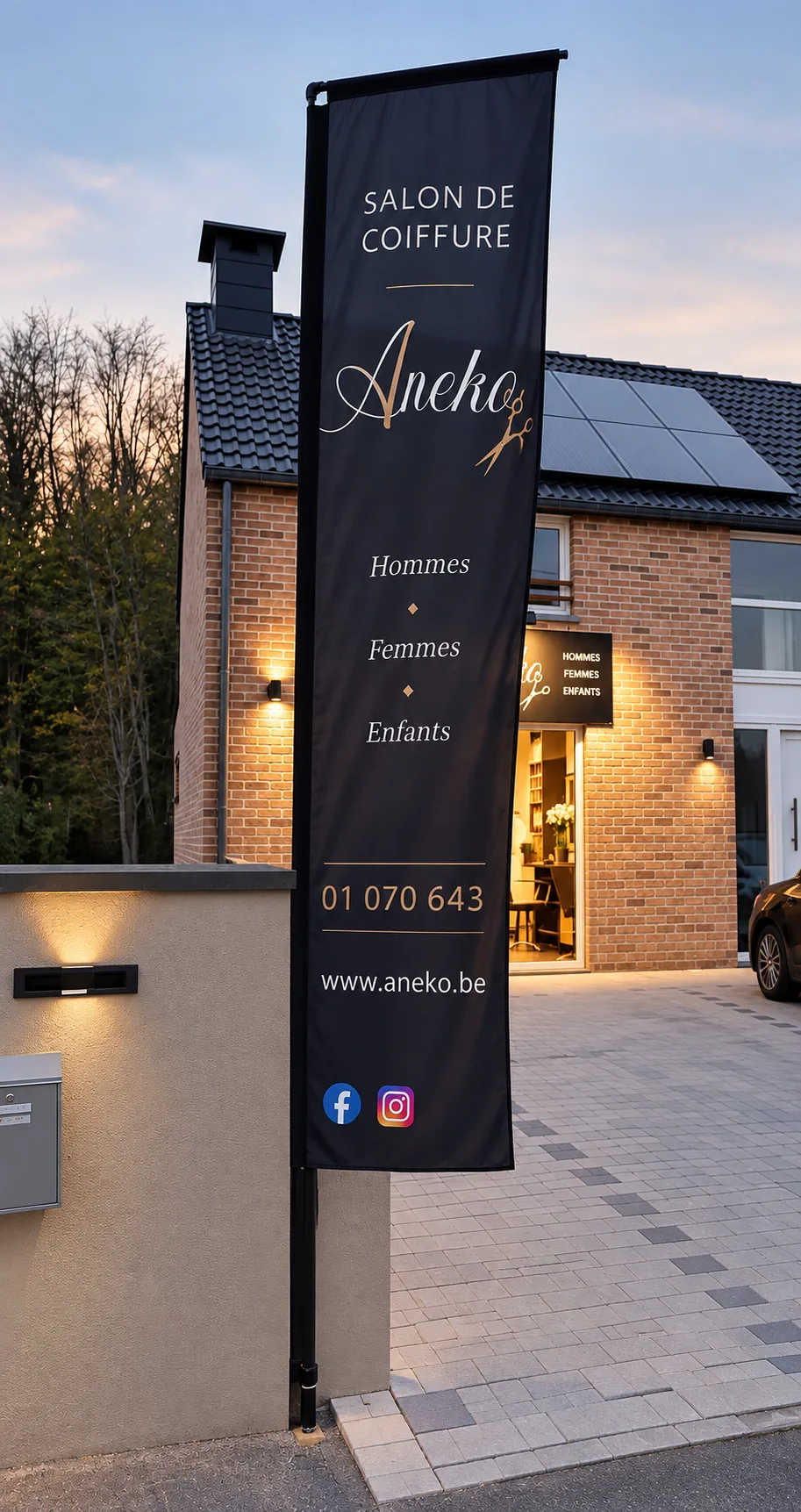 Drapeau publicitaire Aneko devant le salon, au crépuscule